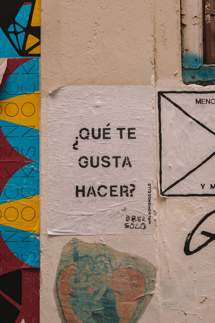 Vibrant graffiti and posters adorn a wall in Valencia, Spain. Urban art at its finest.