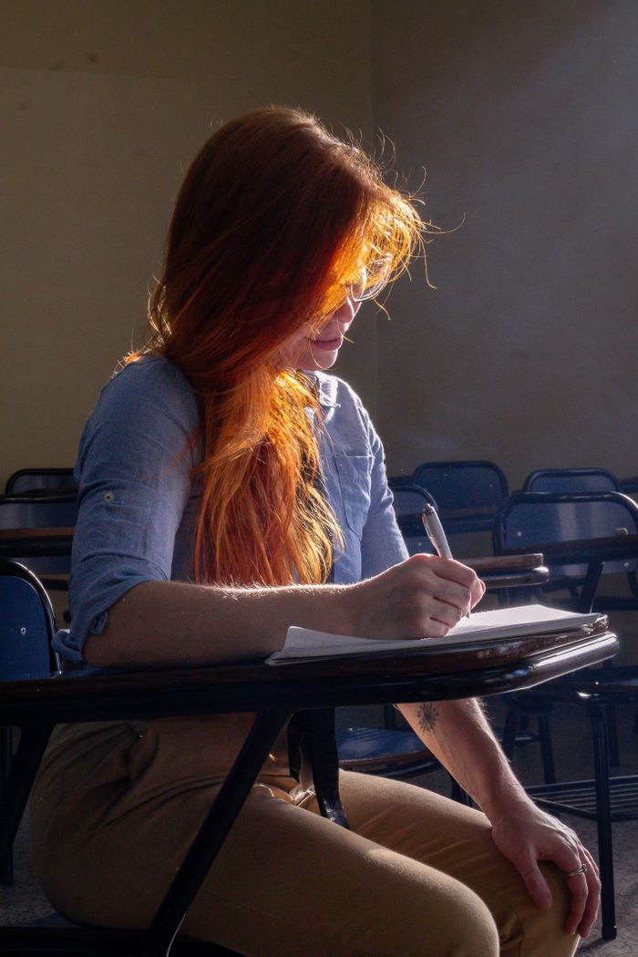 services-03 A young woman with red hair studies in a sunlit classroom in Buenos Aires, Argentina.